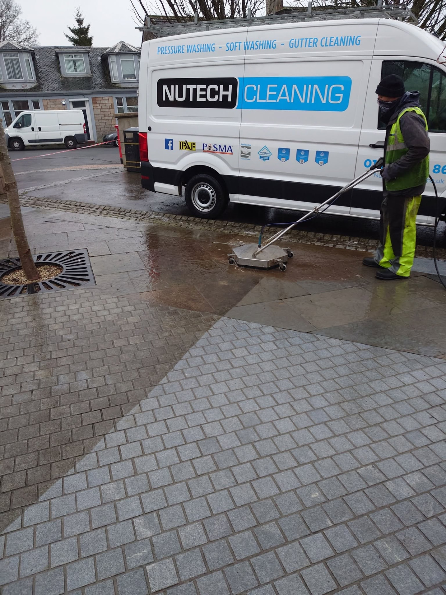 Nutech Cleaning team pressure washing block paving outside a branded van